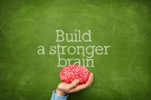 Build a stronger brain on green blackboard with hand holding artificial red brains